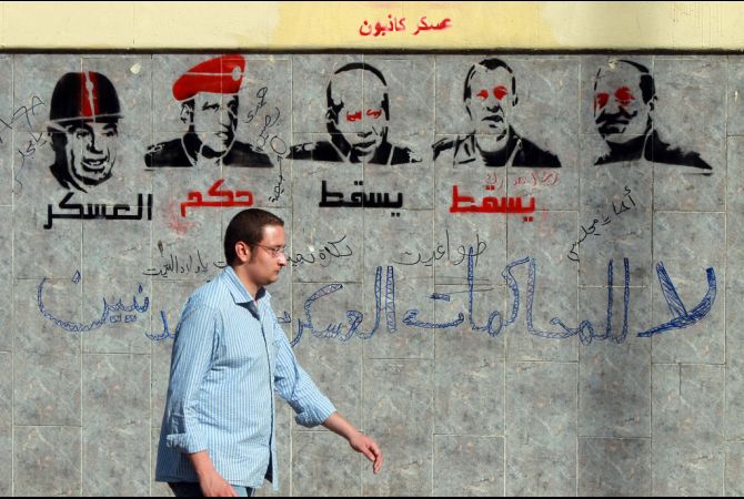 A man walks past graffiti depicting members of the military council and reading 'Down with the military rule, no to military trials for civilians' near the defense ministry in the Abasseya district of Cairo (photo: AFP/KHALED DESOUKI)