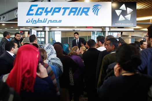 An Egypt Air worker attempts to manage a huge crowd of people looking for flights at Cairo International Airport. Civil Aviation workers are conducting a sit-in because the Civil Aviation Ministry is run by a military man (photo: AFP/Chris Hondros)