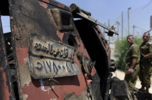 Israeli soldiers inspect a burnt armoured vehicle near the Kerem Shalom border crossing after unidentified gunmen crossed into Israel from Egypt on 6 August. The number plate reads 'Border Guards Forces'   AFP PHOTO/DAVID BUIMOVITCH 