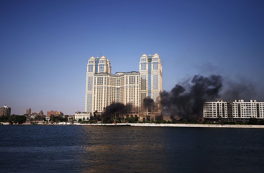 Black smoke rises from burning cars as Egyptian firefighters and bystanders try to extinguish several cars that caught on fire outside the Nile City Towers during clashes on August 2, 2012 (photo: AFP /GIANLUIGI GUERCIA)