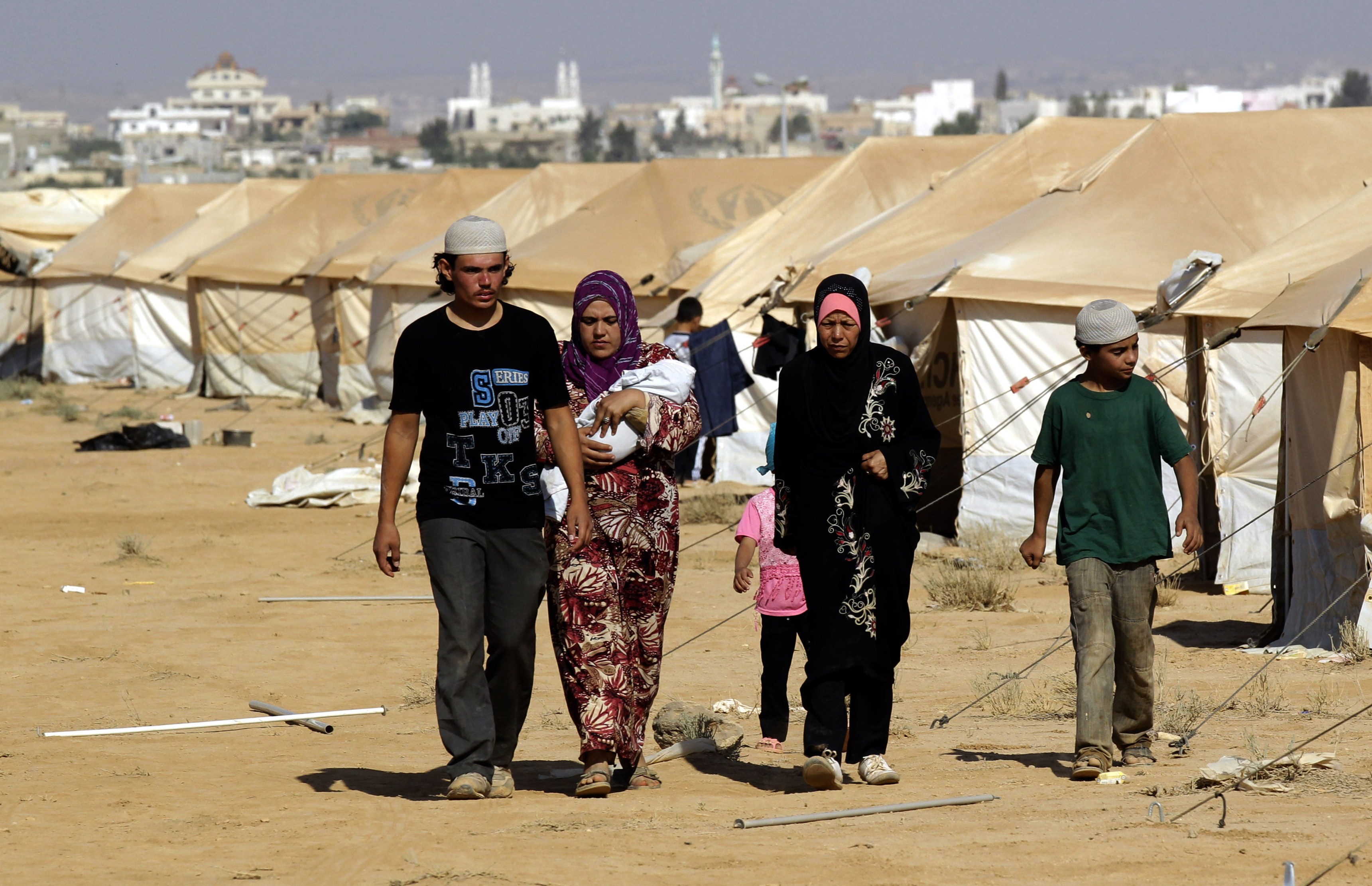 A Syrian family walk past tents at the Zaatari camp near the northern Jordanian city of Mafraq on 12 August, where French medics recently delivered tonnes of supplies and medical equipment AFP PHOTO/KHALIL MAZRAAWI
