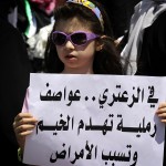 A young girl holds a sign in Arabic that reads "In Zaatari, sand storms destroy tents and cause diseases" during a protest near UN offices in Amman demanding better living conditions at the Zaatari Syrian refugee camp AFP PHOTO/KHALIL MAZRAAWI