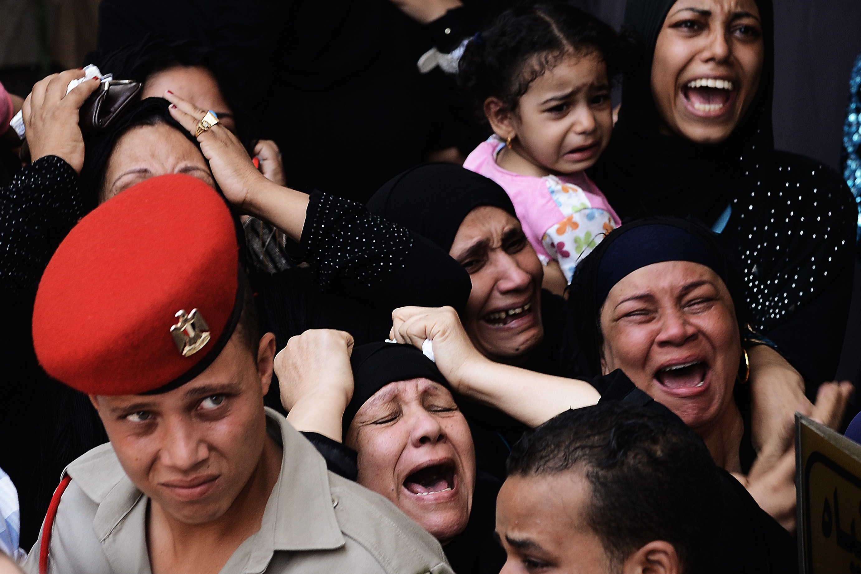 Relatives screams and cry while mourning one of the 16 soldiers killed during an attack on a border crossing post in Northern Sinai, during their funeral on August 7, 2012 in Cairo, Egypt. President Mohamed Morsi ordered security forces to take full control of the Sinai Peninsula and Egypt's army vowed to "avenge" the killings, in which 35 gunmen in Bedouin clothing opened fire on the troops before crossing into the Jewish state in an armoured vehicle, killing five on their side according to the Israelis. AFP PHOTO/GIANLUIGI GUERCIA