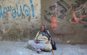 An elderly Palestinian woman sits on the ground outside her home at Al-Shati refugee camp in Gaza City  AFP PHOTO / MAHMUD HAMS 