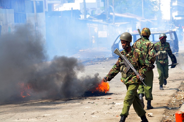 Kenyan paramilitary police walk past burning tyres in Kenya's port city of Mombasa during a second day of clashes after the killing of an extremist cleric linked to Al-Qaeda-allied Shebab militants AFP PHOTO/STRINGER