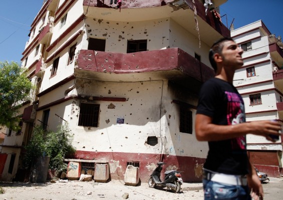 A resident surveys the damage to buildings following clashes off Syria Street in the Lebanese northern port city of Tripoli on 23 August AFP PHOTO / SAM TARLING