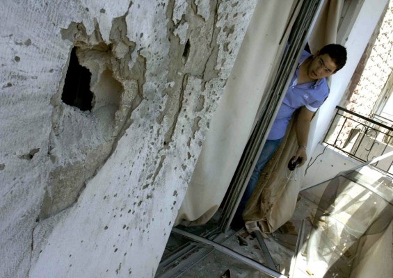 A Lebanese man looks at a hole on a building following a rocket propelled grenade hit in the northern Lebanese city of Tripoli on 22 August AFP PHOTO / Stringer