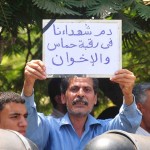 Protester holds a sign at the funeral of the soldiers killed in the Sinai, which literally reads ‘The blood of the martyrs is on the necks of Hamas and the Brotherhood’ blaming the deaths of the soldiers on Hamas and the Muslim Brotherhood organizations.(Photo by Hassan Ibrahim)
