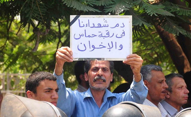 Protester holds a sign at the funeral of the soldiers killed in the Sinai, which literally reads ‘The blood of the martyrs is on the necks of Hamas and the Brotherhood’ blaming the deaths of the soldiers on Hamas and the Muslim Brotherhood organizations.(Photo by Hassan Ibrahim)