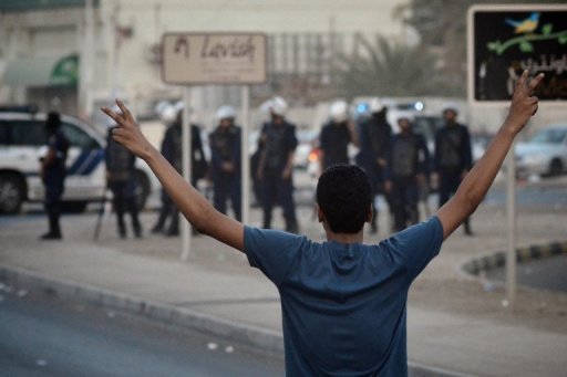 A Bahraini Shiite protester flashes a "V for victory" sign at riot police in June 2012 (AFP Photo)