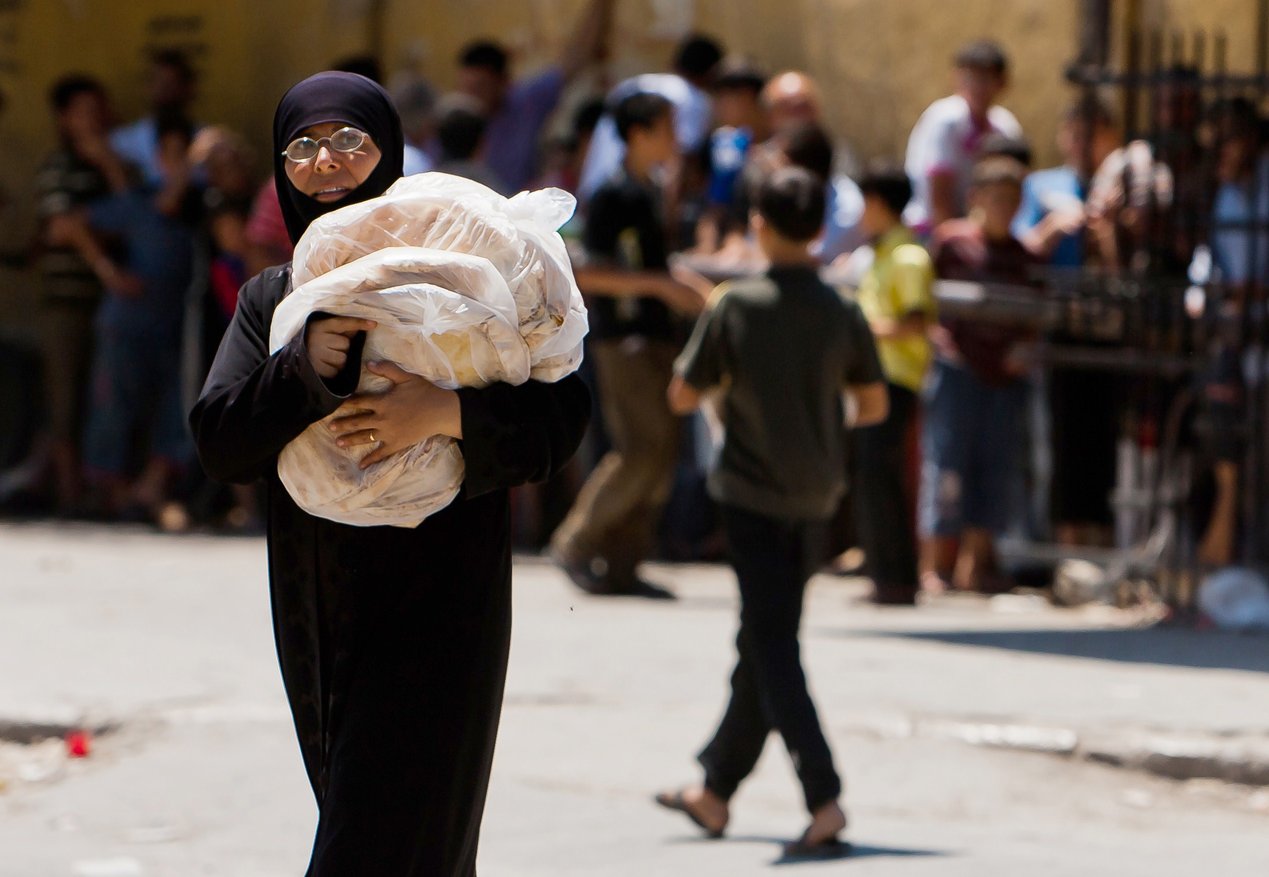 A Syrian woman carries bags of bread in the restive northern Syrian city of Aleppo, on 3 August. Many thousands of Syrian civilians have fled the fighting to other countries, including Egypt AFP PHOTO / VEDAY XHYMSHITI