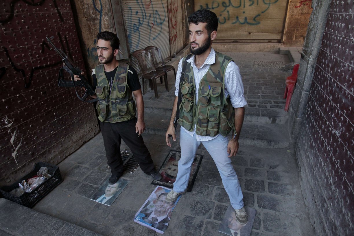 Syrian rebels stand on pictures of Syrian President Bashar Al-Assad as they take position in the northern city of Aleppo on August 3, 2012 (AFP PHOTO/AHMAD GHARABLI)