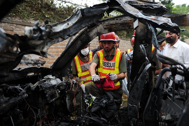 Pakistani rescuers inspect the badly damaged US consulate vehicle at a bomb blast site in Peshawar AFP PHOTO / A MAJEED