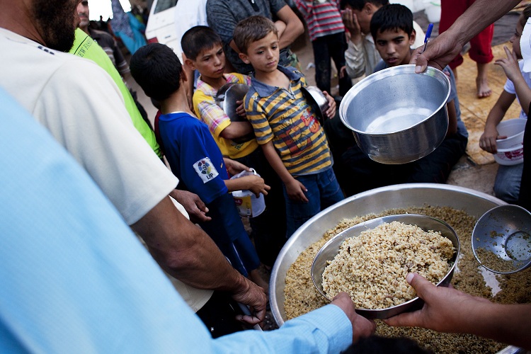 Syrian refugees wait to receive food from a makeshift kitchen in a temporary refugee camp near the Al-Salama crossing between Syrian and Turkey AFP PHOTO / ACHILLEAS ZAVALLIS