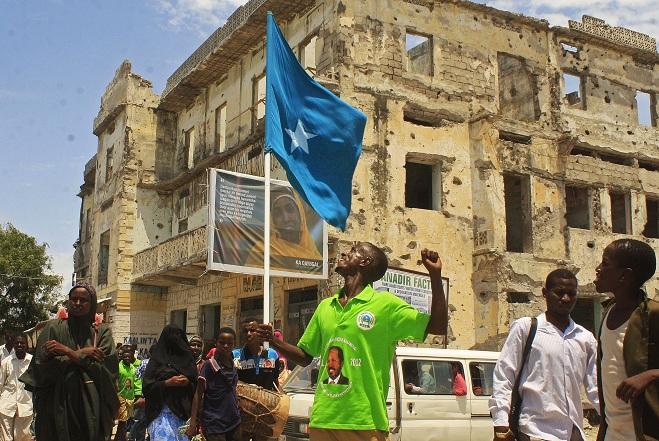 Man wearing a t-shirt with a picture of newly elected Somali President Hassan Sheikh Mohamud on it, waves a Somali flag as he celebrates in southern Mogadishu AFP PHOTO / ABDURASHID ABDULLE ABIKAR