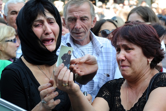 Women cry as they hold the picture of a relative during a protest rally against torture in prisons as demonstrators block one of the capital's main streets in Tbilisi AFP PHOTO / VANO SHLAMOV