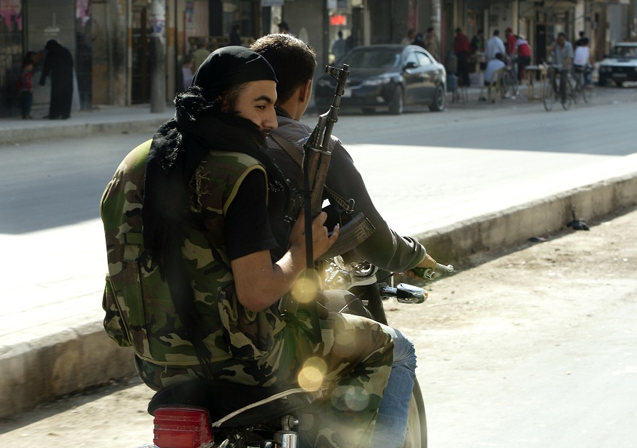 Syrian rebels armed with AK-47s ride a motorcycle in the northern city of Aleppo AFP PHOTO / MIGUEL MEDINA