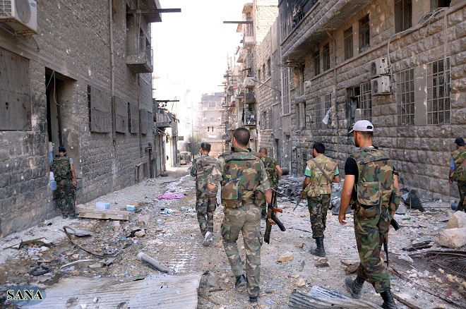Syrian government forces walking along a street strewn with debris in the northern city of Aleppo during fighting against rebel forces AFP PHOTO / HO / SANA