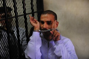 Alber Saber stands for trial in the defendent'ss cage    Hassan Ibrahim / DNE