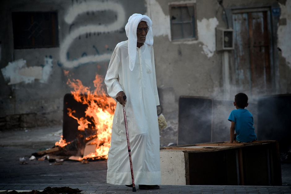 An elderly Bahraini man walks past a burning barricade set-up by protesters during clashes with the police following a demonstration in solidarity with jailed Bahraini opposition activists in Malekia, on the outskirts of the capital Manama on 4 September AFP PHOTO / MOHAMMED AL-SHAIKH