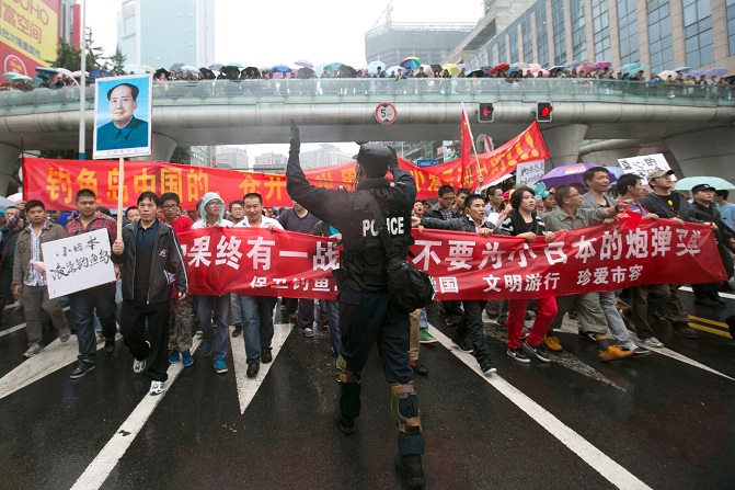 Chinese policeman directs protesters as they march and display anti-Japanese banners during a protest over the Diaoyu islands issue in Chengdu, southwest China's Sichuan province AFP PHOTO