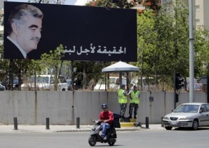 A Lebanese man rides his motorbike past a poster of slain premier Rafik Hariri in Beirut  AFP/File, Joseph Eid