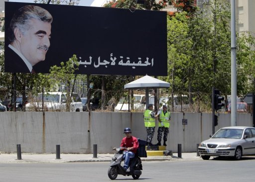 A Lebanese man rides his motorbike past a poster of slain premier Rafik Hariri in Beirut AFP/File, Joseph Eid