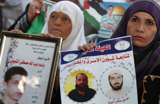 Palestinian women hold pictures of prisoners held in Israeli jails during a protest in Ramallah AFP / Abbas Momani