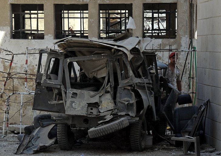 A handout picture released by the Syrian Arab News Agency (SANA) shows a member of the Syrian security forces inspecting the wreckage of a vehicle in Al-Mehdi Street in the Abu Remmaneh district of the Syrian capital Damascus on September 2, 2012 as Syrian state TV reported twin bombings near security service buildings in the centre of the capital and said they wounded four people. AFP PHOTO/HO/SANA