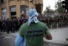 A supporter of the March 14 movement, which opposes the Syrian regime of President Bashar al-Assad, stands facing Lebanese security forces during a demonstration outside the governmental palace in Beirut after the funeral of top intelligence chief General Wissam al-Hassan and his bodyguard, in downtown Beirut, on October 21, 2012. Lebanese police fired in the air and used tear gas to repel protesters trying to storm the office of Lebanese Prime Minister Najib Mikati, amid calls for him to quit. (AFP Photo / Florian Choblet)