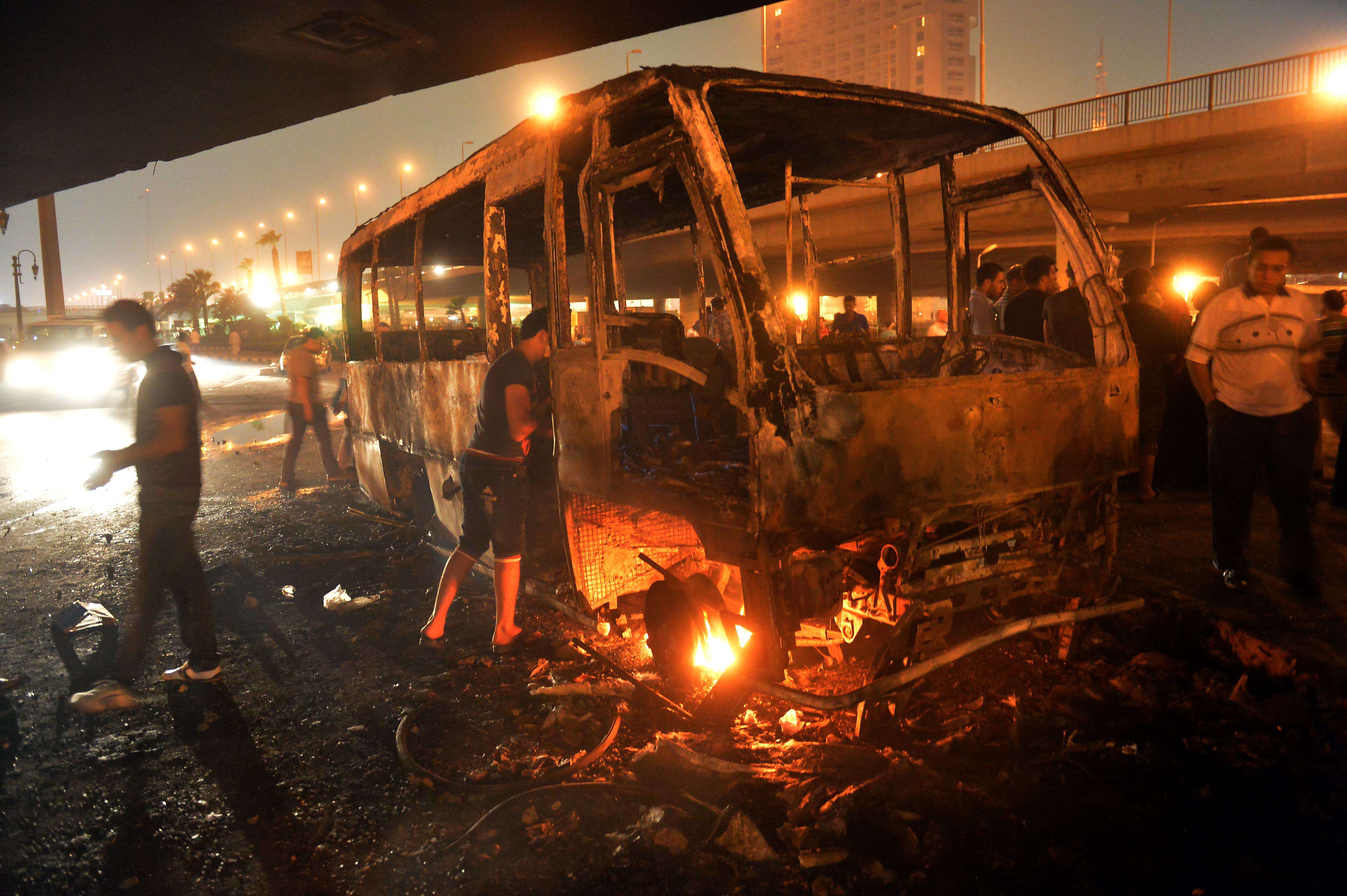 Egyptians inspect a burnt bus which was set on fire during clashes between government supporters and opponents of the Muslim Brotherhood and President Mohamed Morsi in Tahrir square in Cairo. (AFP/ KHALED DESOUKI)
