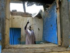 A man points to damage at his house caused by rebel fire. (AFP/ Ashraf Shazly)