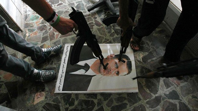 Free Syrian Army soldiers point guns at a portrait of President Bashar Al-Assad. (AFP PHOTO / ADEM ALTAN)