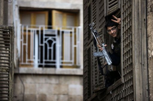 A Syrian student-turned-rebel makes a victory sign from his post in an ancient building in Aleppo (Photo by AFP / John Cantlie)
