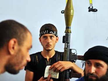 A fighter from the Syrian opposition holds a Koran, Islam's holy book, and a rocket-propelled grenade (RPG). (AFP PHOTO / BULENT KILIC)
