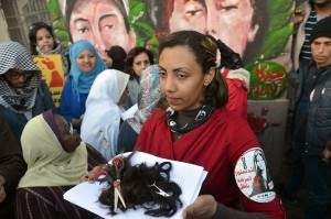 Fatma Al-Sharif holds a bunch of hair cut from female protesters during a symbolic demonstration by Egyptian women against their country's new constitution draft. (AFP Photo / Khaled Desouki)