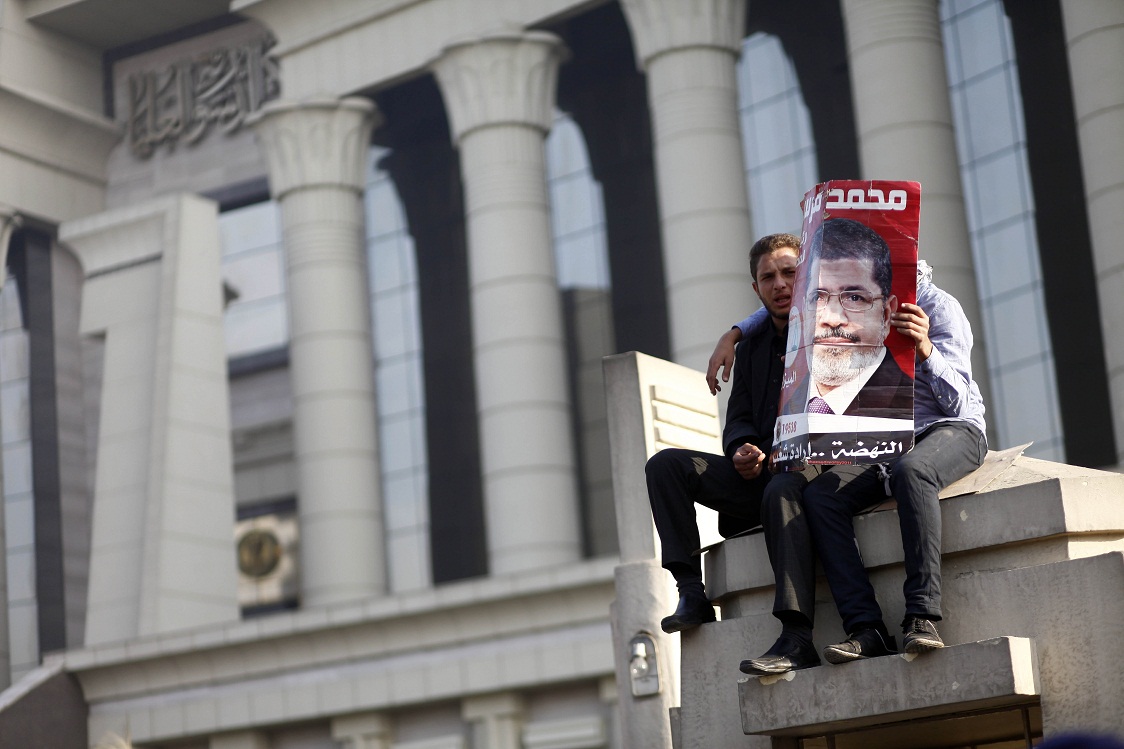 Two men hold a portrait of President Morsy as hundreds of his supporters protest outside a top Egyptian court, forcing judges to postpone a hearing on a constitutional panel at the heart of a deepening political crisis AFP Photo / Mahmoud Khaled