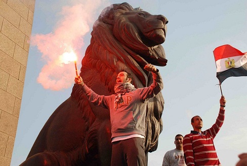 A man burns a flare while stood on the Qasr Al-Nile bridge, passed by a march to Tahrir Square to protest against President Morsy’s perceived consolidation of power. (DNE/ Hassan Ibrahim)