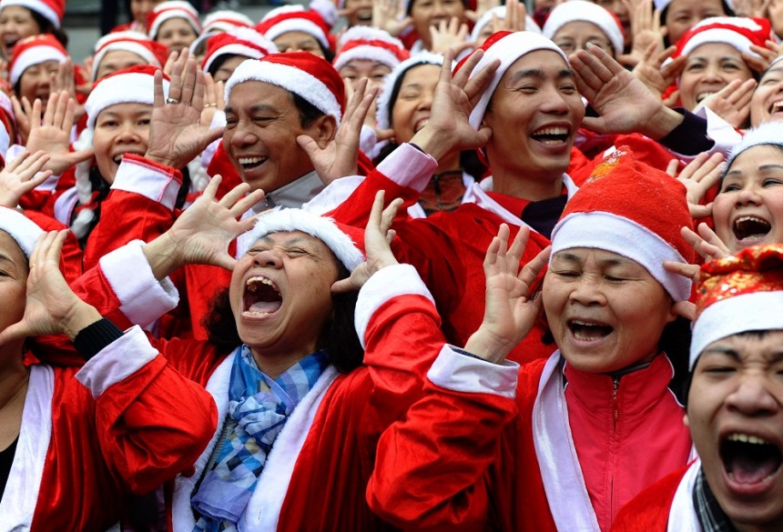 Members of a local Smiling Yoga club wearing Santa Claus costumes at they perform at a public park in Hanoi . Churches, shops, restaurants and shopping malls are decorated in the Southeast Asian nation with some six million Catholics preparing to celebrate Christmas. AFP Photo / Hoang Dinh Nam