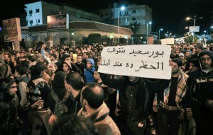 An Egyptian protester holds up a banner as demonstrators march in the streets of the canal city of Port Said late on January 28, 2013 breaking the curfew the government imposed on the city and two other provinces  AFP PHOTO / STR