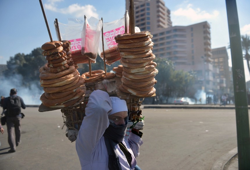 A street vender selling bread walks past as a tear gas canister fired by riot police during clashes with protesters near Tahrir Square AFP Photo / Khaled Desouki