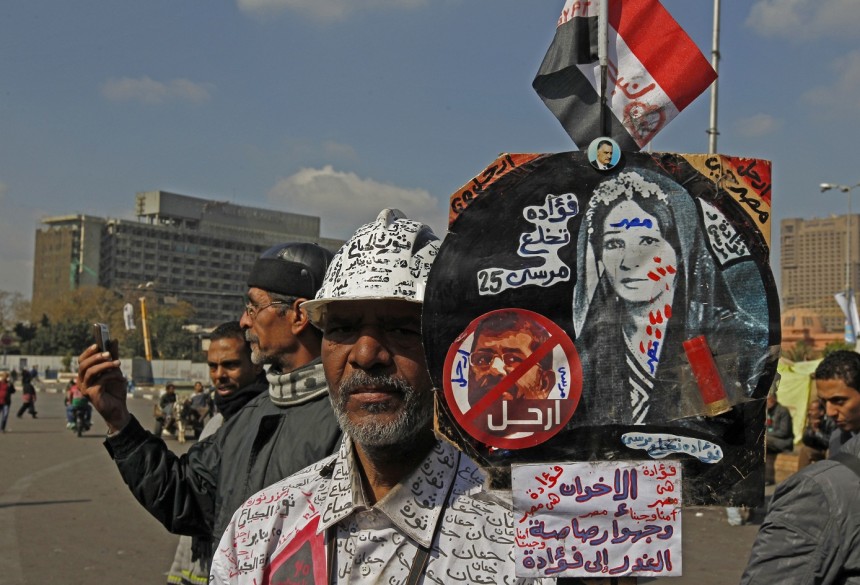A protester wearing a shirt and carrying a banner covered in anti-Muslim Brotherhood text stands in Tahrir Square on 29 AFP Photo / Mohammed Abed