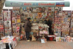 A newspaper vendor (right) talks to a customer at her booth on a street in Shanghai on 8 January 2013.(AFP/ Peter Parks)