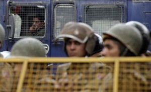 Police are seen watching protesters from behind a barrier during a rally in New Delhi, on 30 December 2012. (AFP PHOTO)