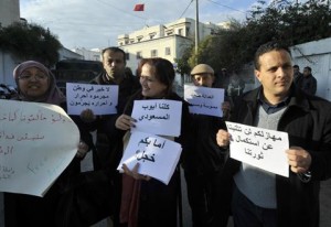 Ayoub Messaoudi (R), former adviser of the Tunisian president, and supporters hold placards as he arrives for his trial on appeal at a military court on January 4, 2013 in Tunis. Arabic writing on sign held by the woman (C) reads: "We are all Ayoub Messaoudi". AFP PHOTO / FETHI BELAID