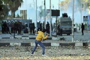 A protester throws a stone towards Egyptian riot police in the Suez Canal city of Port Said on 5 March 2013 (AFP Photo \ Stringer)