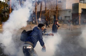 An Egyptian protester throws back tear gas canisters during clashes with riot police near Tahrir Square in Cairo Yesterday