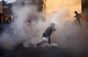 An Egyptian protester throws tear gas canisters back during clashes with riot police near Tahrir Square in Cairo  (AFP Photo)
