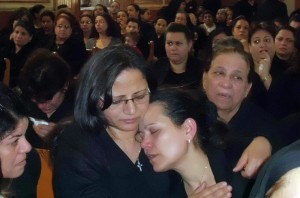 Egyptian Coptic Christian Ragaa Abdullah (C-R) wife of Ezzat Hakim Attallah, who died in the eastern Libyan city of Benghazi, days after being arrested on charge for allegedly seeking to convert Muslims in Libya, mourns with relatives during his funeral service at a church in Assiut city (AFP Photo)