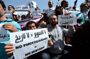 Egyptian photojournalists hold signs in English and Arabic, including one reading "Freedom to the camera" (R), during a demonstration outside the Shura council in Cairo on March 19, 2013  (AFP File Photo)